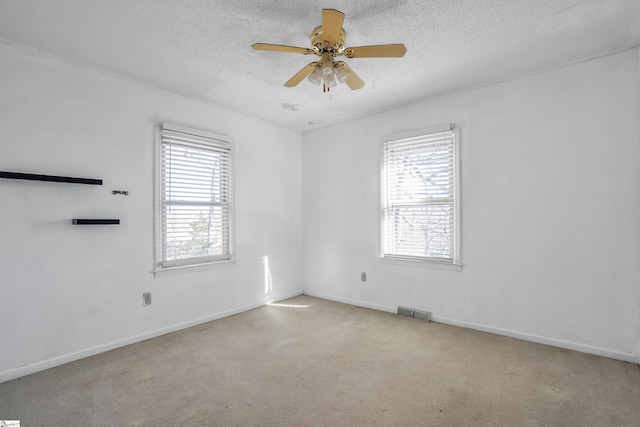 carpeted spare room featuring ceiling fan, a textured ceiling, and a healthy amount of sunlight