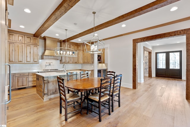 dining area featuring sink, ornamental molding, light hardwood / wood-style floors, beam ceiling, and french doors