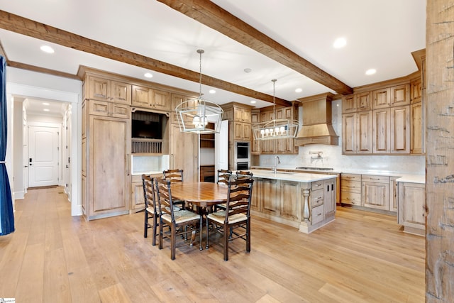 kitchen with premium range hood, sink, tasteful backsplash, hanging light fixtures, and an island with sink