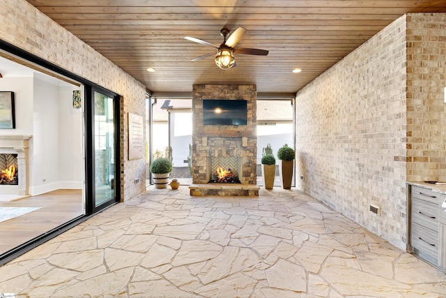 view of patio / terrace featuring ceiling fan and an outdoor stone fireplace