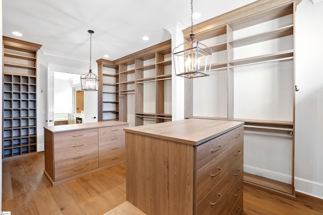 spacious closet featuring a chandelier and light hardwood / wood-style floors