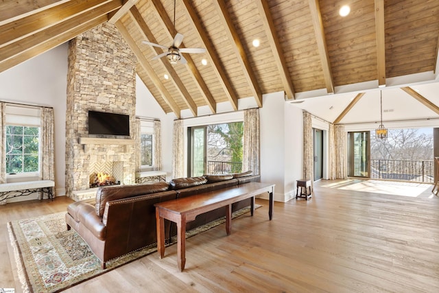 living room featuring beamed ceiling, a fireplace, a wealth of natural light, and wooden ceiling