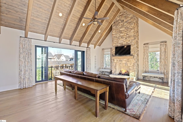 living room with beam ceiling, a fireplace, high vaulted ceiling, and light hardwood / wood-style floors