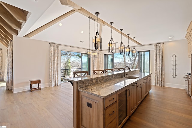 kitchen featuring hanging light fixtures, a wealth of natural light, sink, and dark stone countertops