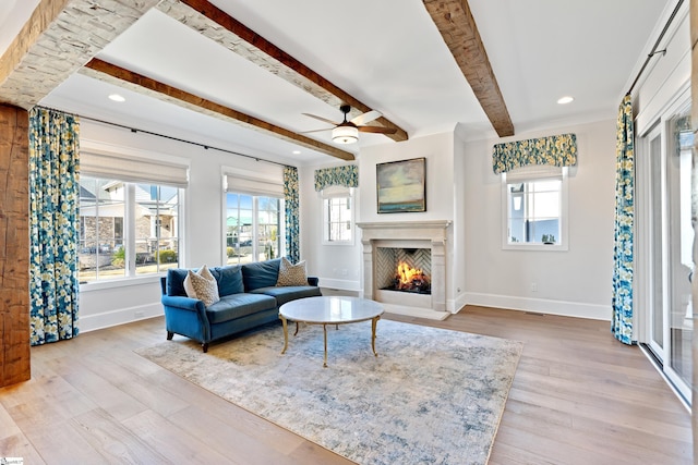 living room with light wood-type flooring, a wealth of natural light, and beam ceiling