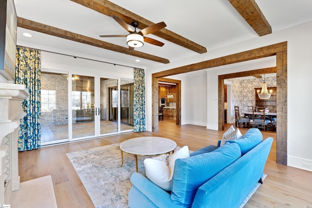 living room featuring ceiling fan with notable chandelier, light hardwood / wood-style floors, and beamed ceiling