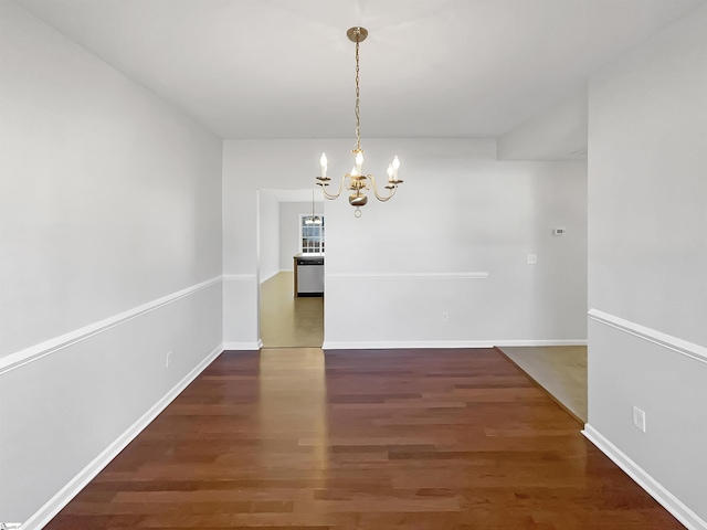 unfurnished dining area featuring dark wood-type flooring and a chandelier