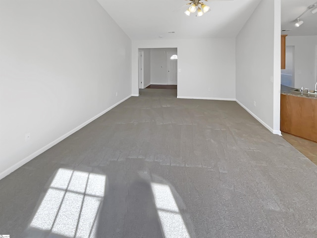 unfurnished living room with sink, ceiling fan, and dark colored carpet