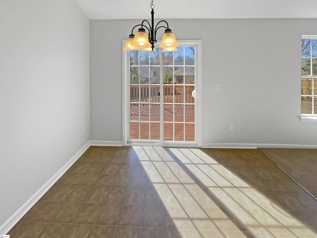 unfurnished dining area with dark tile patterned flooring and a notable chandelier