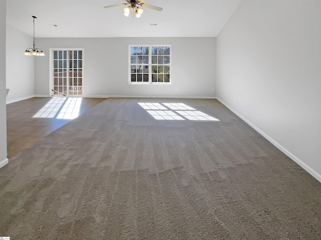 spare room with ceiling fan with notable chandelier, a healthy amount of sunlight, and carpet