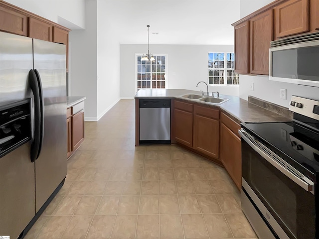 kitchen featuring appliances with stainless steel finishes, decorative light fixtures, sink, light tile patterned floors, and kitchen peninsula