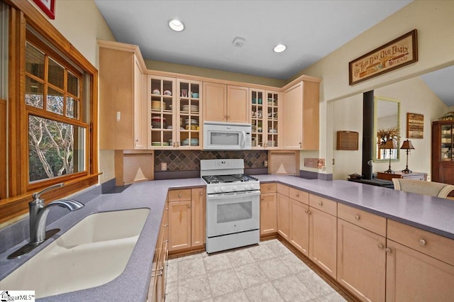 kitchen with sink, light brown cabinets, kitchen peninsula, white appliances, and backsplash