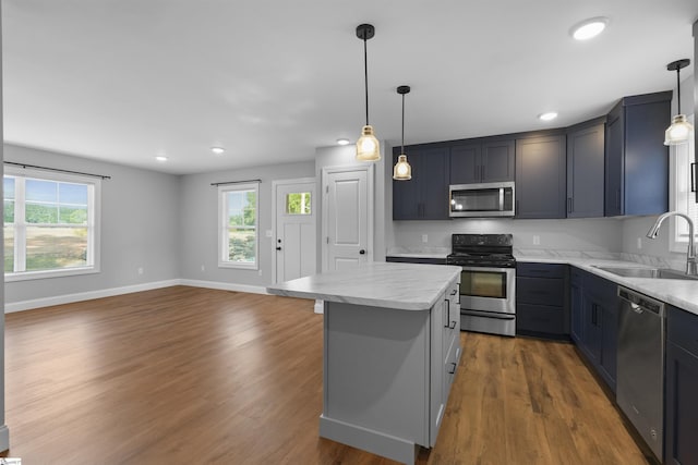 kitchen with a center island, appliances with stainless steel finishes, sink, and decorative light fixtures