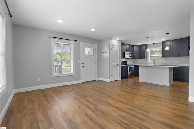 kitchen featuring appliances with stainless steel finishes, dark hardwood / wood-style flooring, a center island, and hanging light fixtures