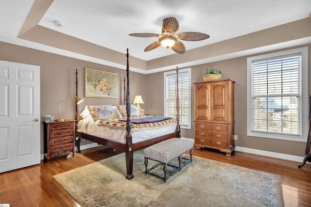 bedroom with a tray ceiling, light hardwood / wood-style flooring, and ceiling fan