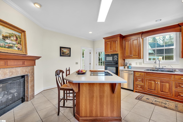 kitchen featuring sink, a breakfast bar area, a center island, light tile patterned floors, and black appliances