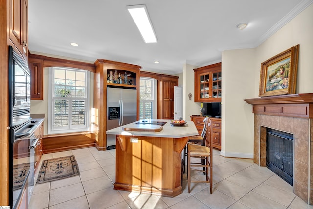 kitchen with a breakfast bar area, crown molding, a center island, light tile patterned floors, and stainless steel fridge