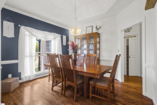 dining space featuring ornamental molding, dark wood-type flooring, a chandelier, and a tray ceiling