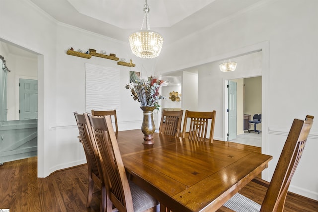 dining space featuring dark hardwood / wood-style flooring, a notable chandelier, crown molding, and a raised ceiling