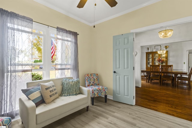 sitting room featuring ornamental molding, ceiling fan with notable chandelier, and light wood-type flooring