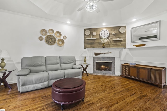 living room with ceiling fan, ornamental molding, a stone fireplace, and hardwood / wood-style floors