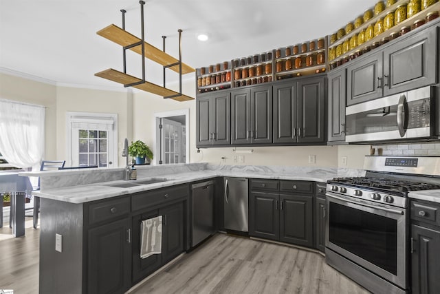 kitchen featuring sink, crown molding, appliances with stainless steel finishes, light stone countertops, and kitchen peninsula