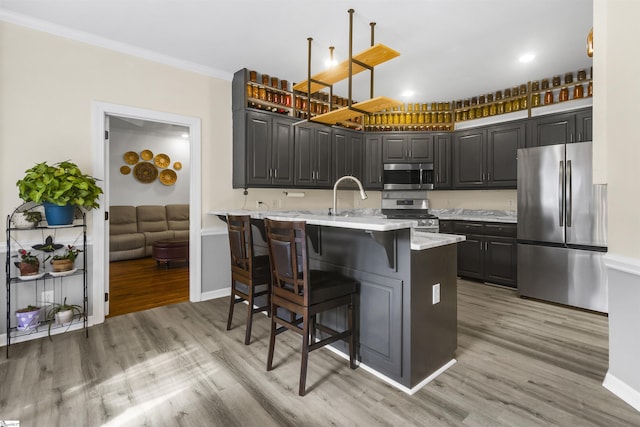 kitchen with appliances with stainless steel finishes, kitchen peninsula, a breakfast bar area, and light hardwood / wood-style flooring