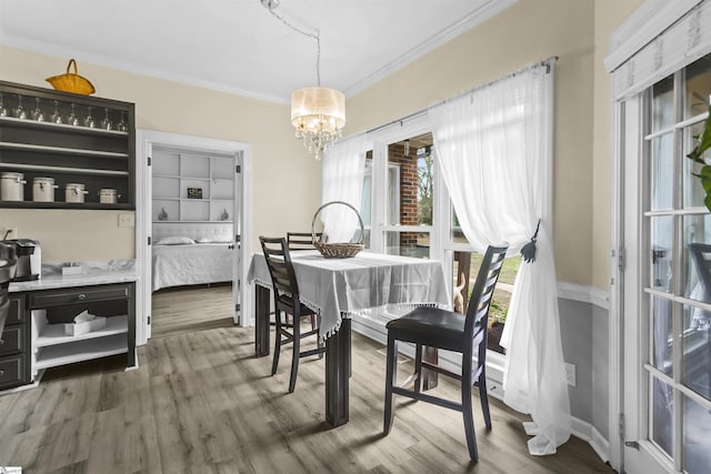 dining area featuring hardwood / wood-style flooring, crown molding, and a notable chandelier