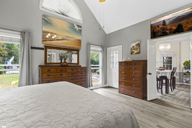 bedroom with multiple windows, a notable chandelier, access to outside, and high vaulted ceiling