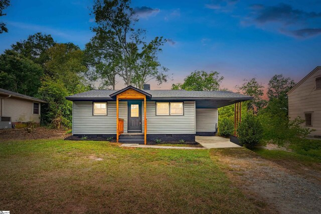 ranch-style home with a carport, central AC, and a lawn