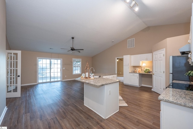 kitchen with an island with sink, sink, white cabinets, stainless steel fridge, and dark hardwood / wood-style flooring