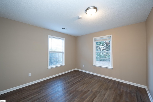 empty room with a textured ceiling and dark hardwood / wood-style flooring