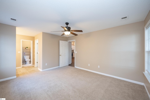 unfurnished bedroom with ceiling fan, ensuite bathroom, and light carpet