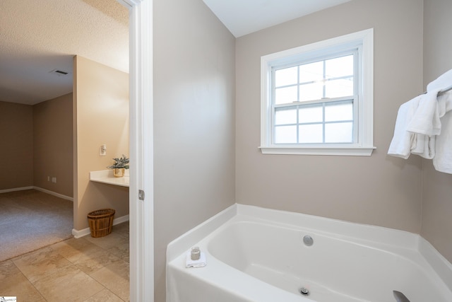 bathroom with a tub to relax in and a textured ceiling