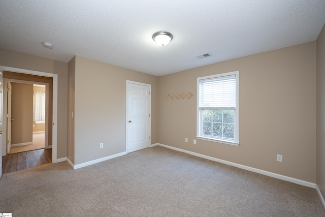 carpeted empty room featuring a textured ceiling