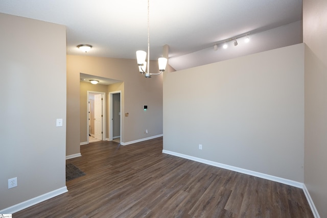 empty room with dark hardwood / wood-style flooring, lofted ceiling, and a chandelier