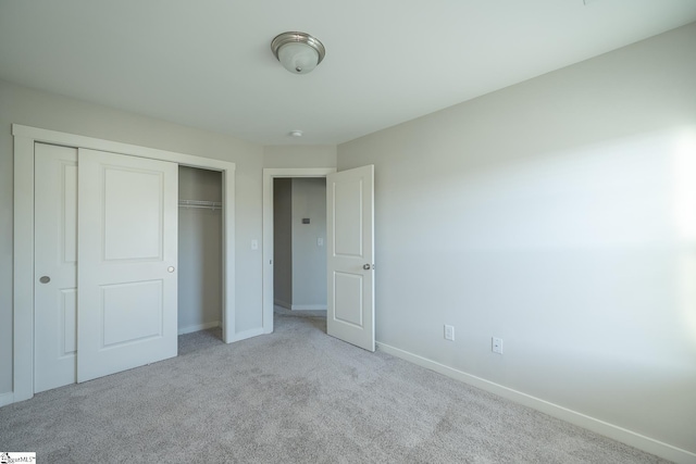 unfurnished bedroom with light colored carpet and a closet