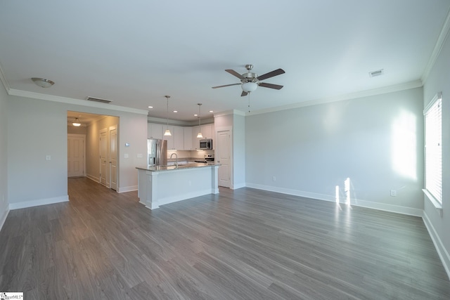 interior space featuring appliances with stainless steel finishes, pendant lighting, white cabinetry, an island with sink, and dark wood-type flooring