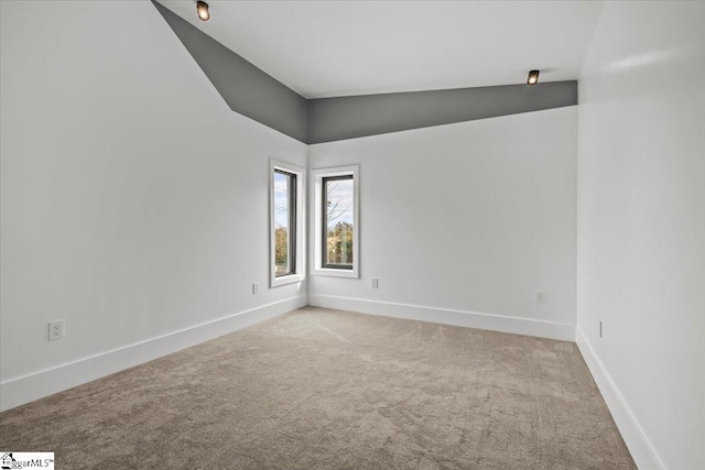 carpeted spare room with lofted ceiling