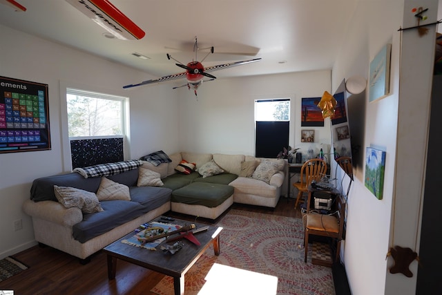 living room with a wealth of natural light, dark hardwood / wood-style floors, and ceiling fan