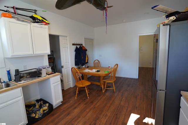 kitchen with white cabinets, dark wood-type flooring, sink, and stainless steel fridge