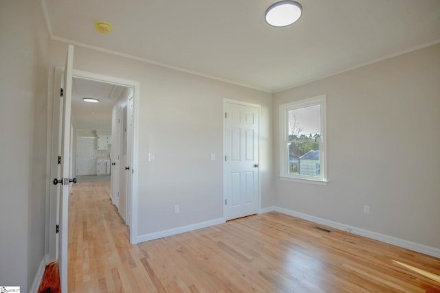 empty room with crown molding and light hardwood / wood-style flooring