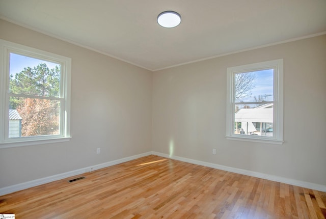 spare room featuring crown molding and light hardwood / wood-style floors