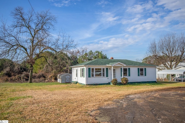 single story home featuring a carport, a front yard, and a storage shed