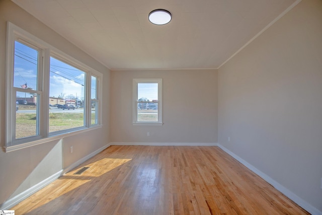 empty room with ornamental molding and light hardwood / wood-style flooring