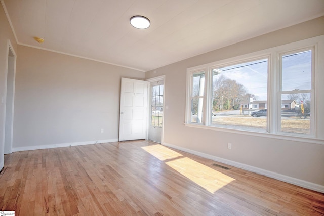 spare room with crown molding, light hardwood / wood-style floors, and a healthy amount of sunlight