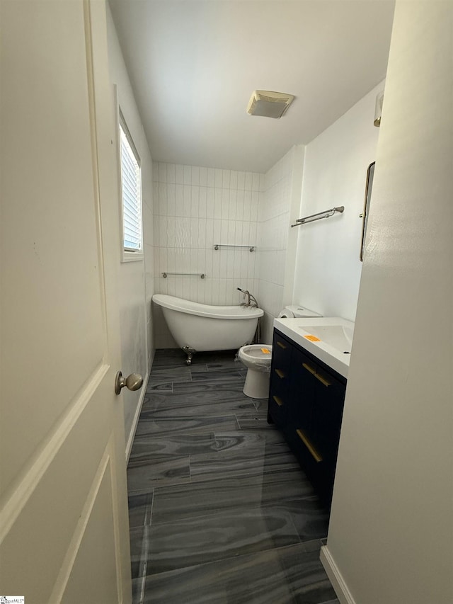 bathroom with a washtub, vanity, and toilet