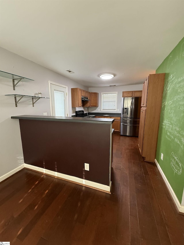 kitchen featuring stove, dark hardwood / wood-style flooring, stainless steel fridge, and kitchen peninsula