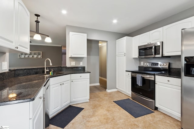 kitchen featuring pendant lighting, sink, stainless steel appliances, white cabinets, and dark stone counters