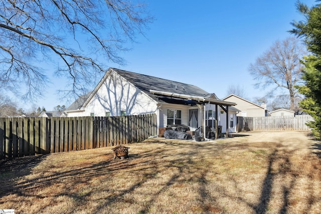 back of house featuring a yard and an outdoor fire pit